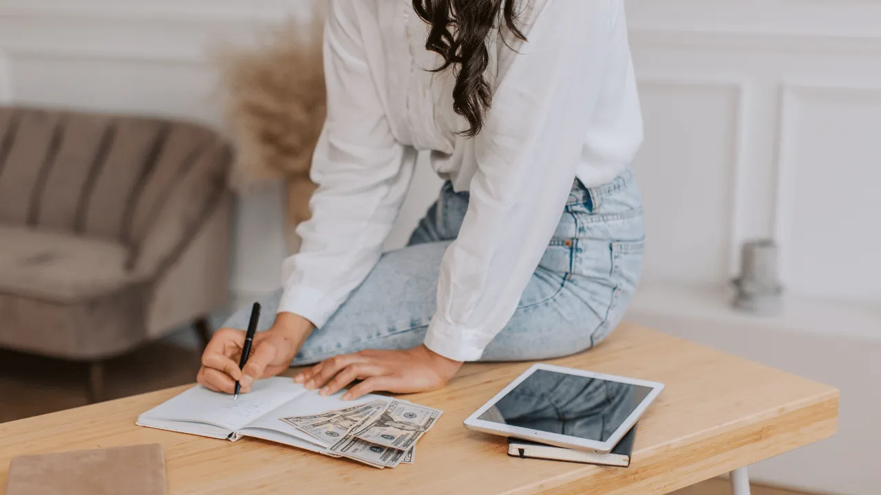 A creator writing at home beside a smartphone and project budget
